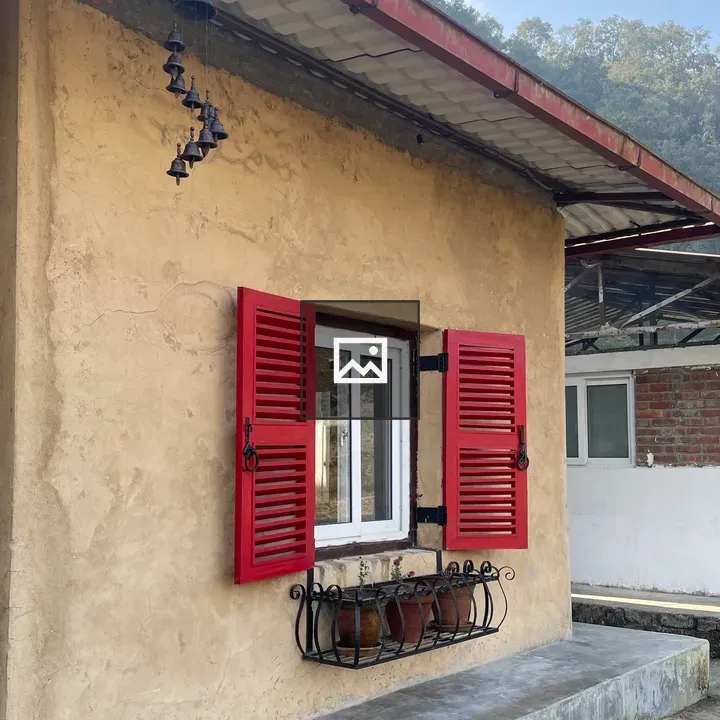 Small rustic house with red shutters