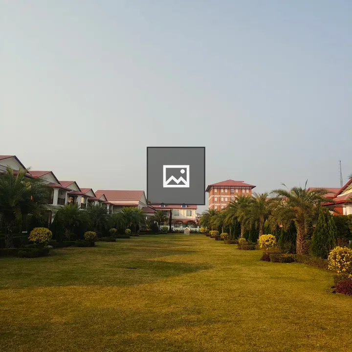 Grassy area with hedges and buildings