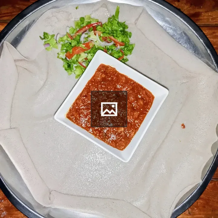 Top-down Eritrean meal with tibsi and injera