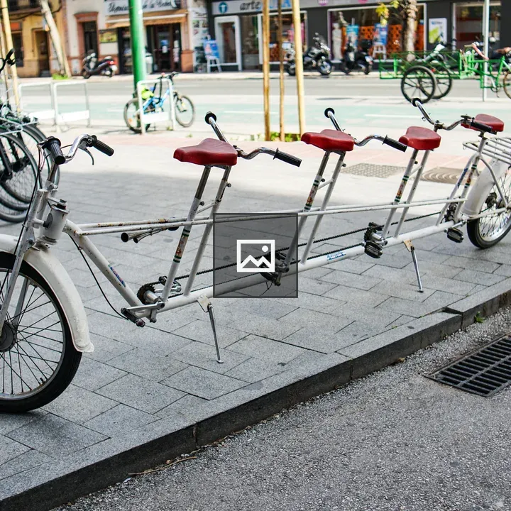 Long tandem bike with red saddles