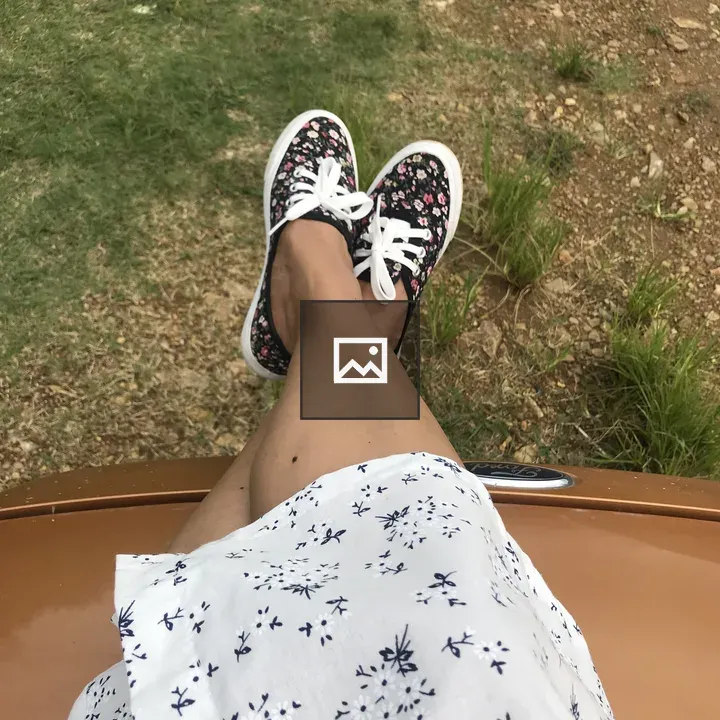 Legs in white floral skirt and black sneakers