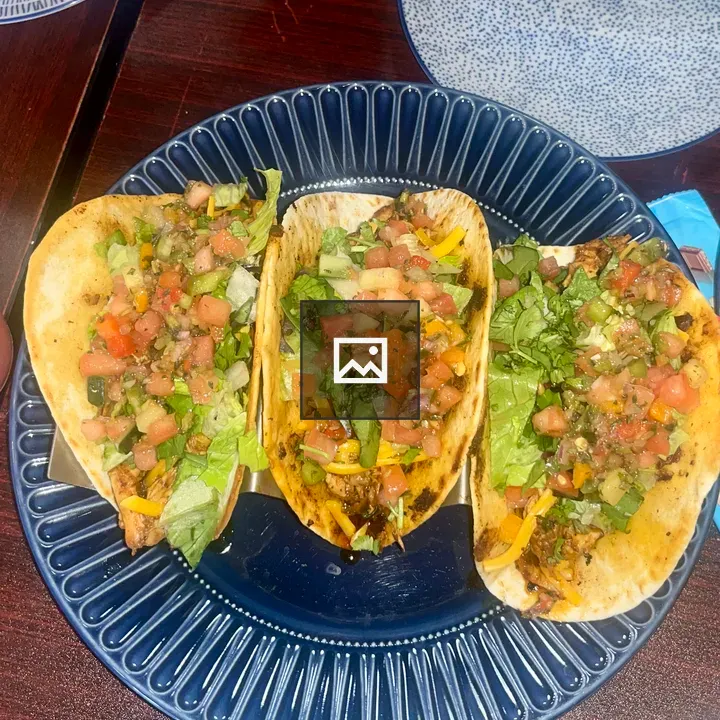 Three tacos on dark plate