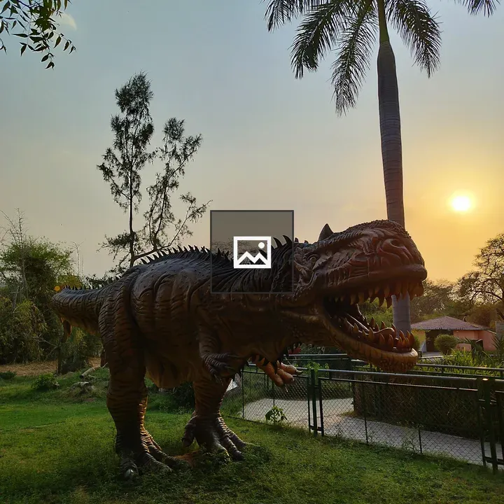 Dinosaur statue in grassy garden