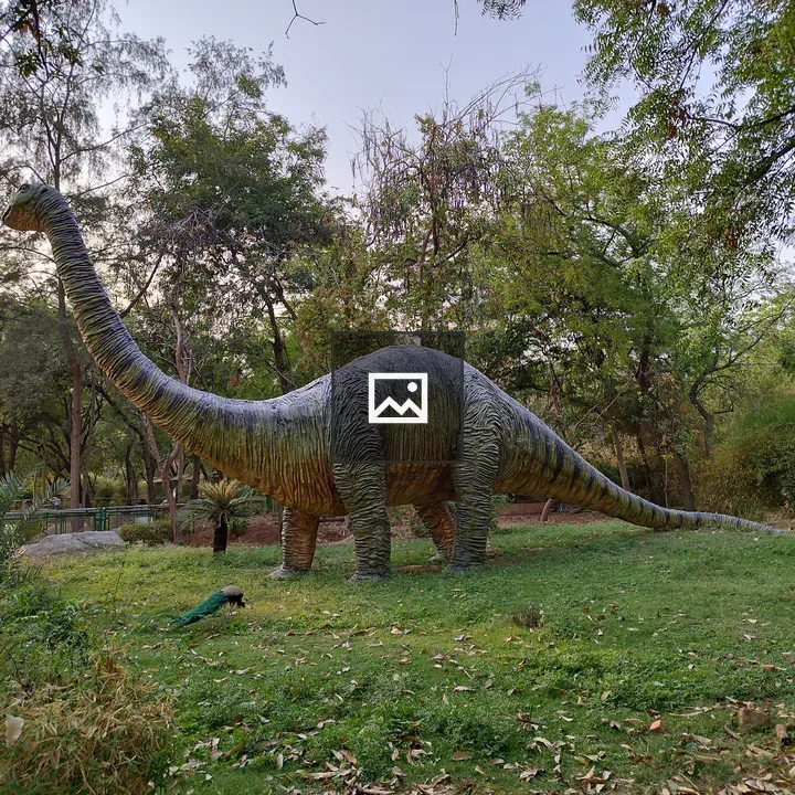 Dinosaur statue with peacock nearby