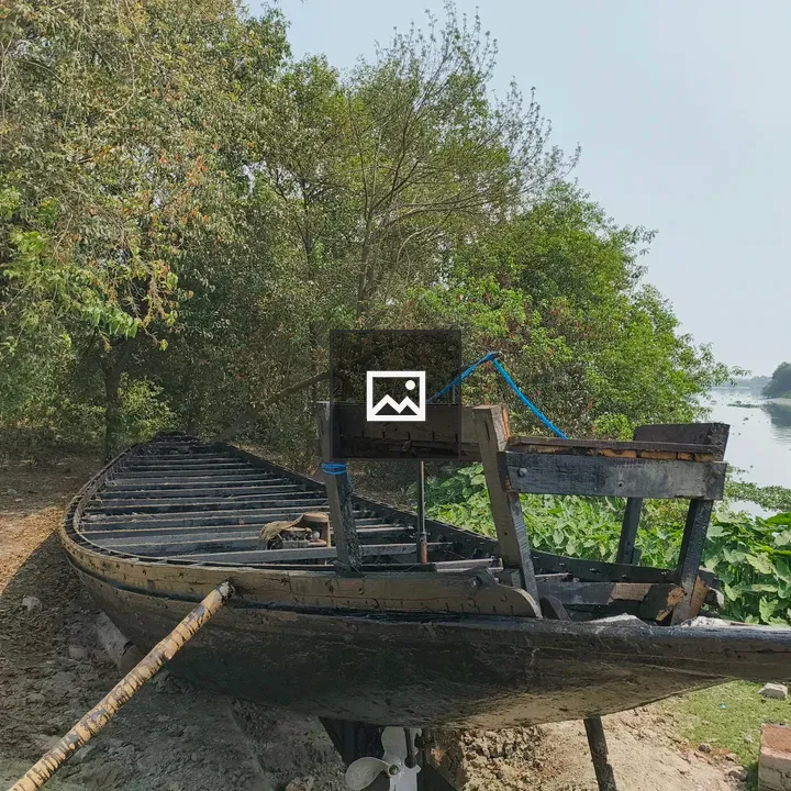 Wooden Boat on Shore by Green Riverbank
