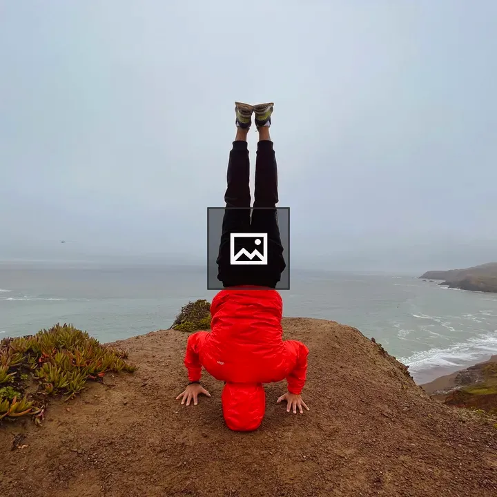 Person doing headstand on cliff side