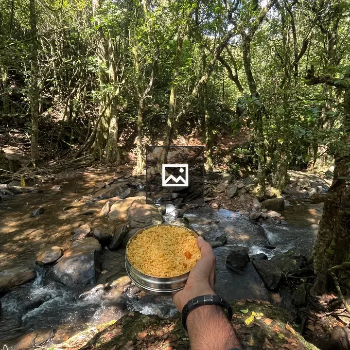 Person holding bowl of yellow noodles