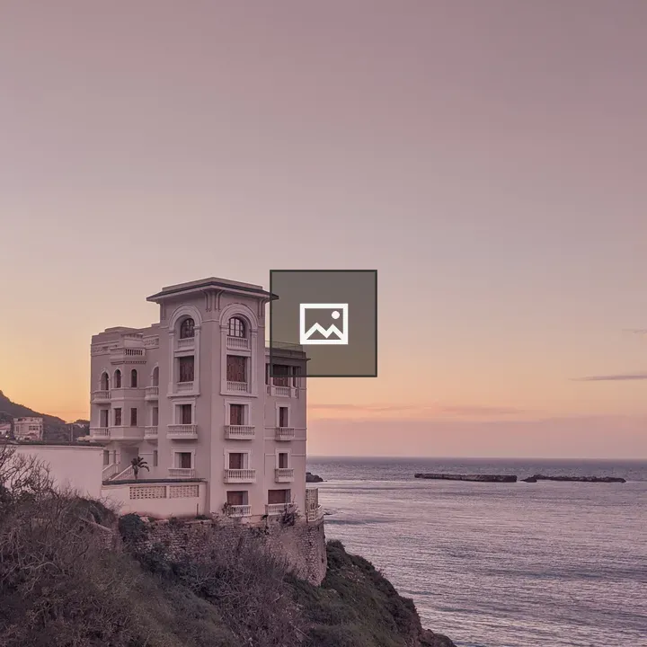 White building on cliff at sunset