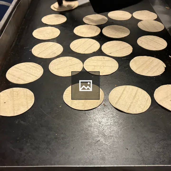 Griddle with Tortillas Being Flipped