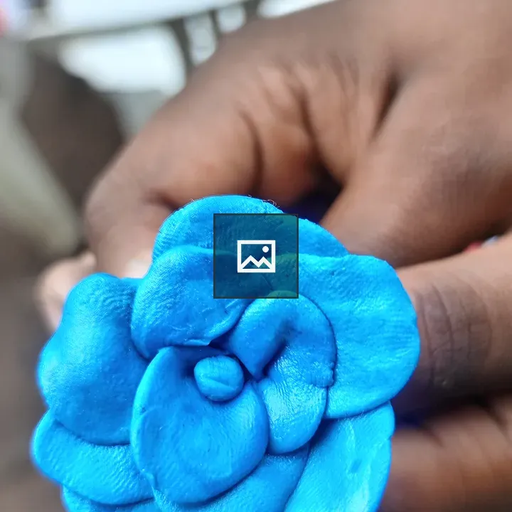 Blue clay rose held by hand