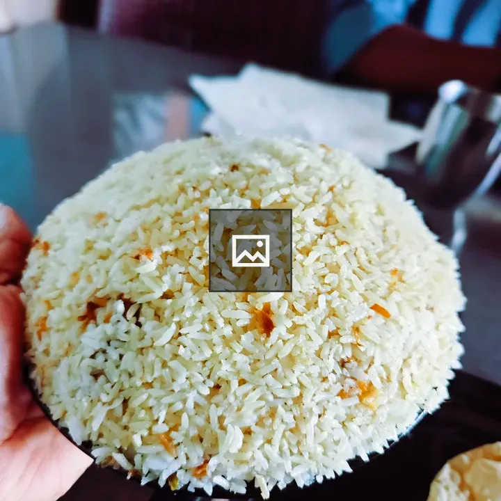 Hand holding plate of fluffy Malabar biryani