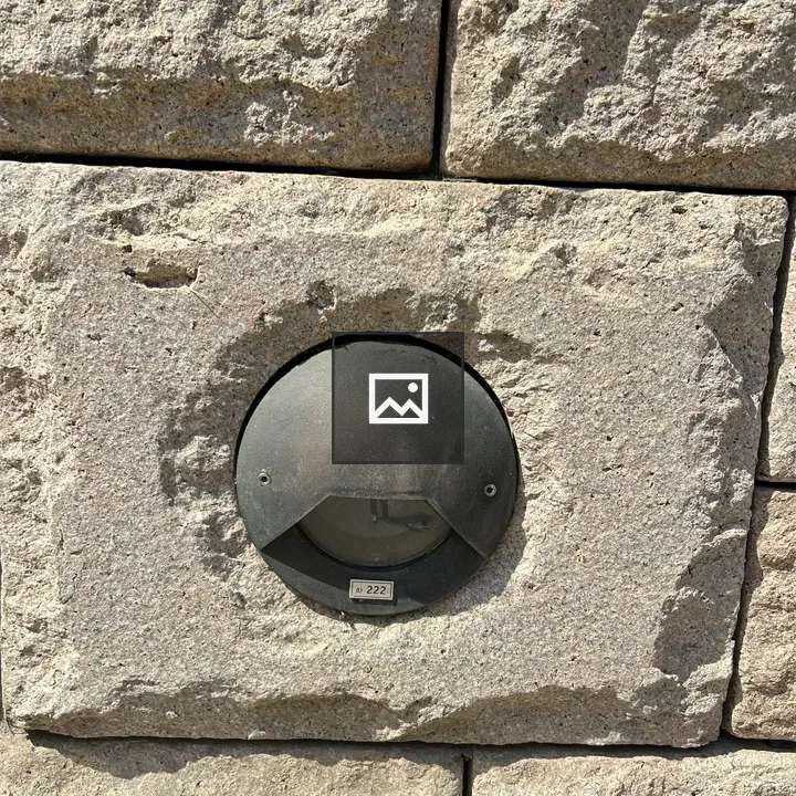Circular black light fixture on gray stone wall
