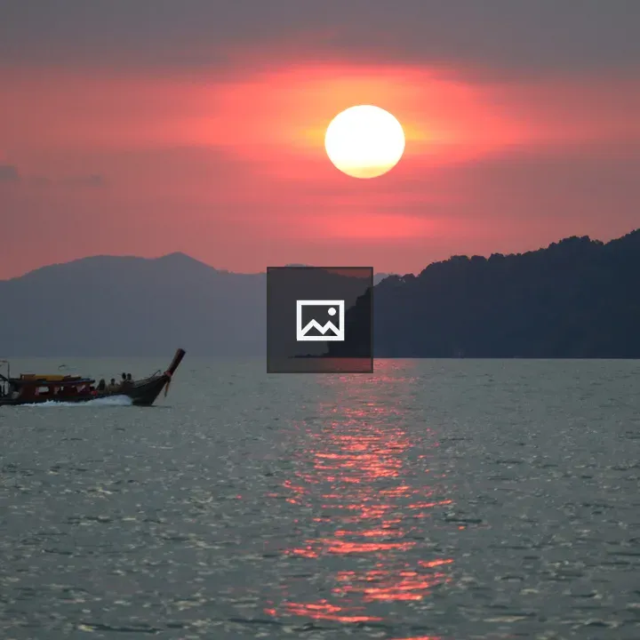 Solitary boat at sunset over mountains