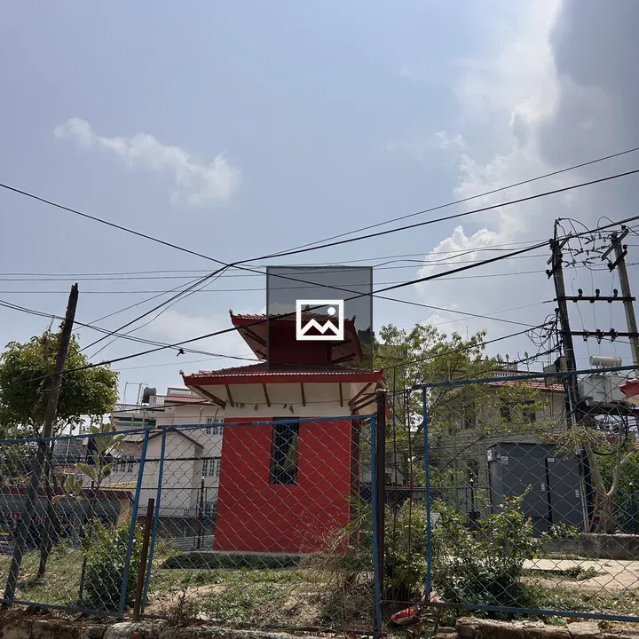 Small red temple behind fence