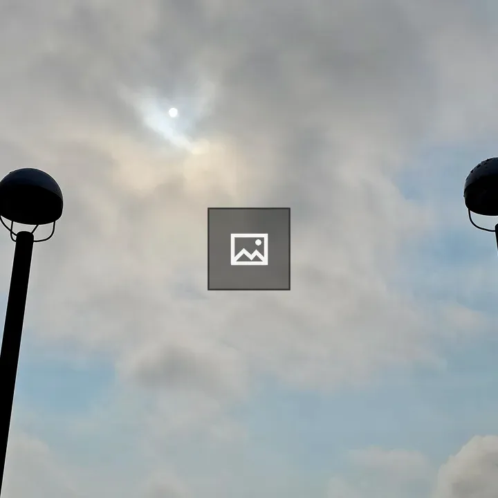 Two lampposts against cloudy sky