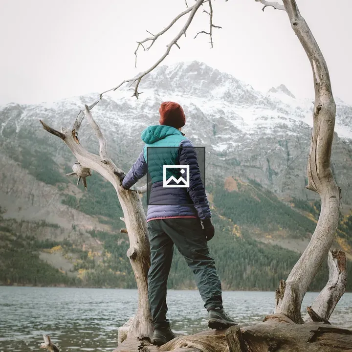 Person in winter hiking gear looking over lake and mountains
