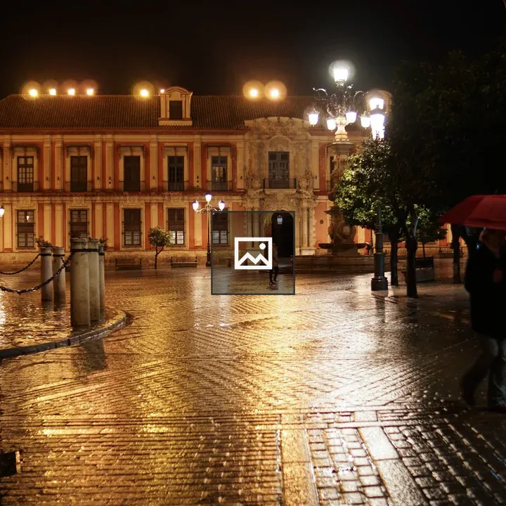 Nighttime street with lit building and umbrella