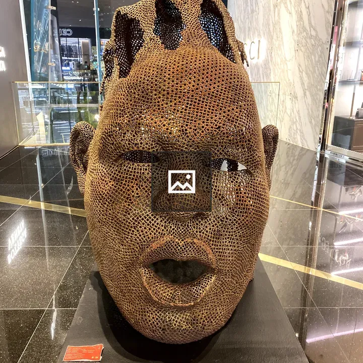 Metal sculpture of a head on pedestal