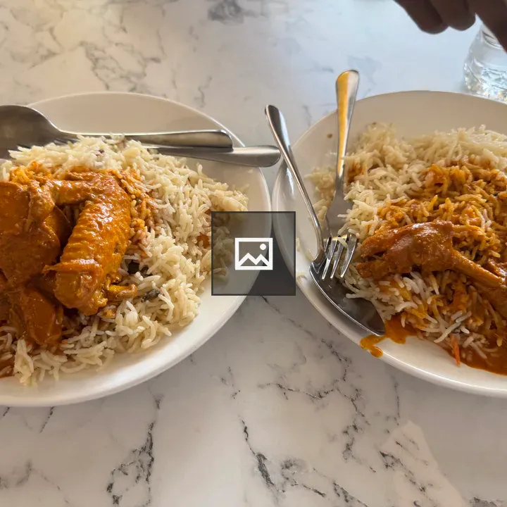 Two plates of chicken over rice