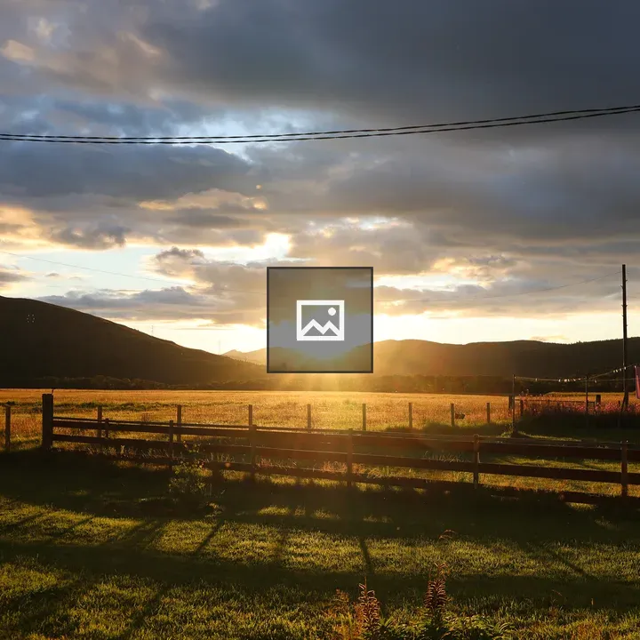 Sunset over fields by mountain fence