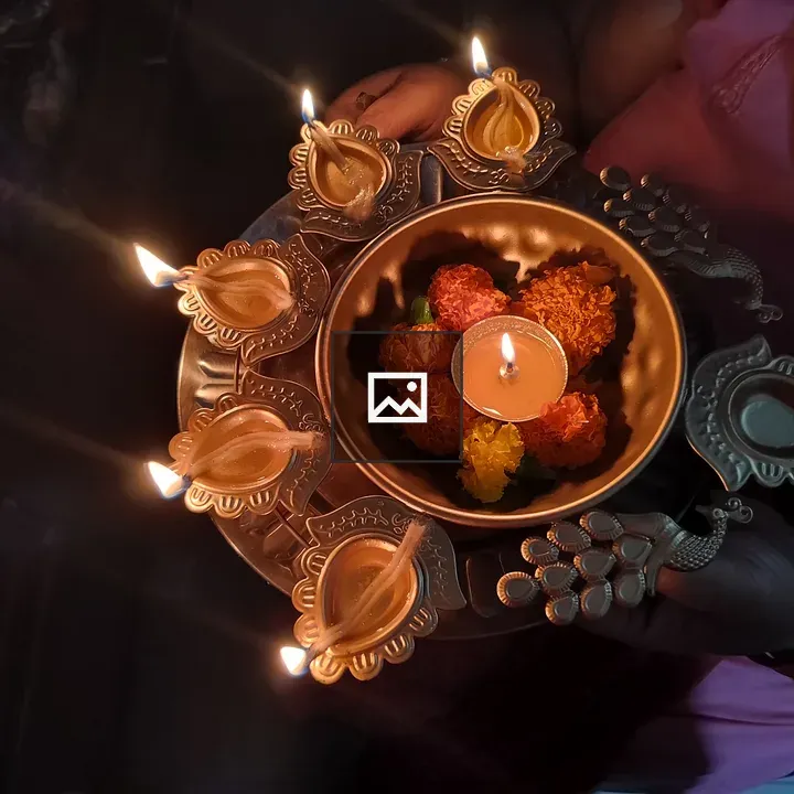 Person with lit diyas and flowers