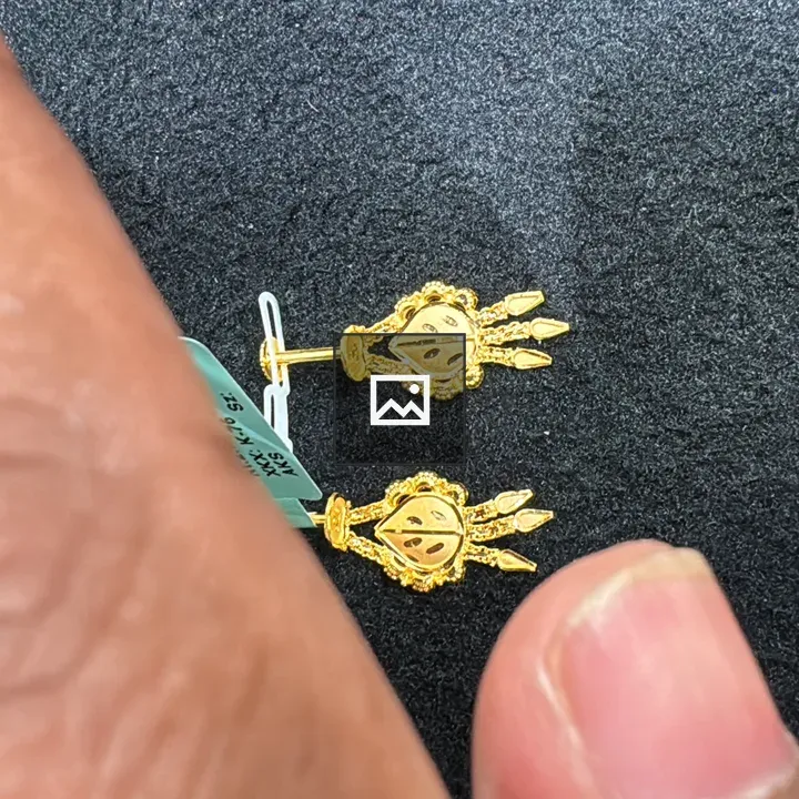 Gold earrings held against black background