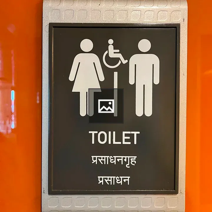 Black restroom sign on orange wall