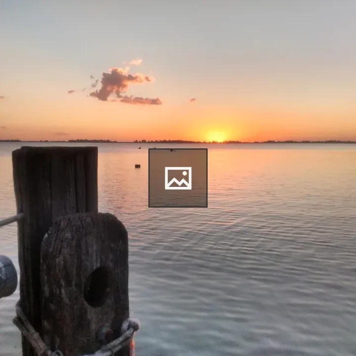 Sunset over water with wooden posts