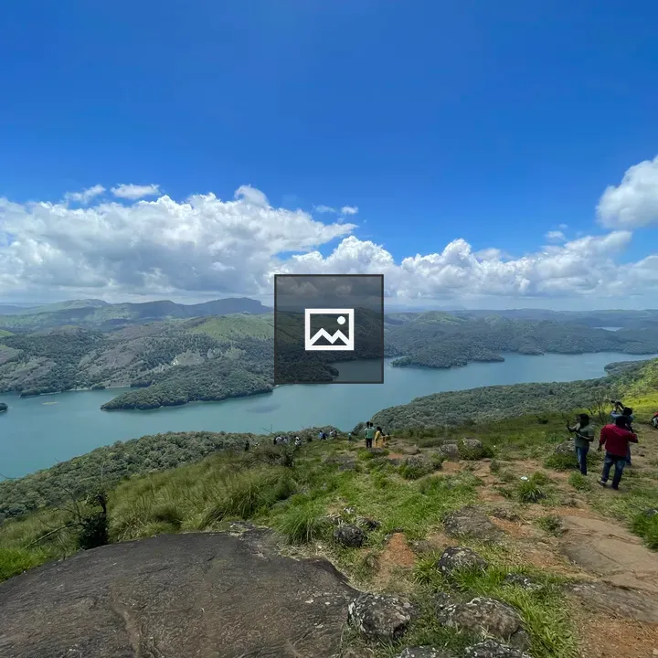 People on grassy hillside overlooking lake and mountains