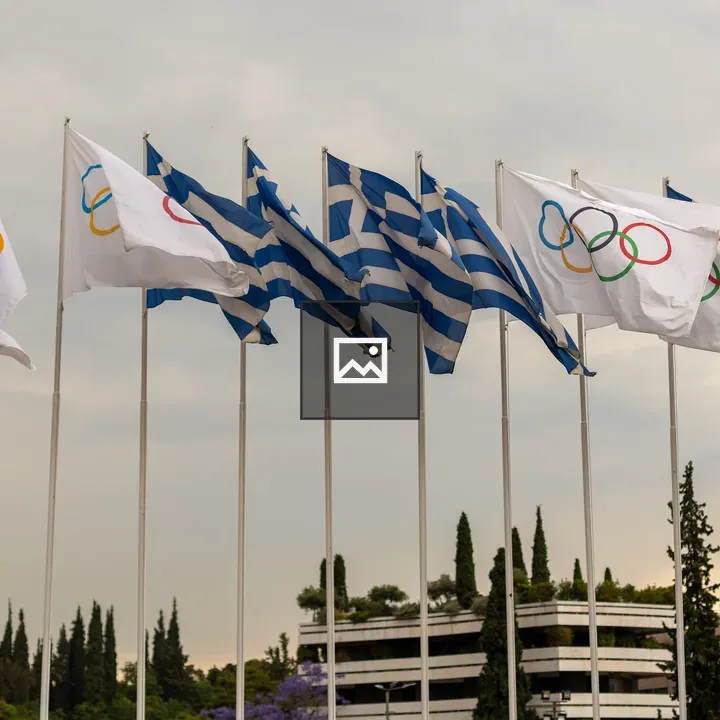 Greek and Olympic flags at sunset