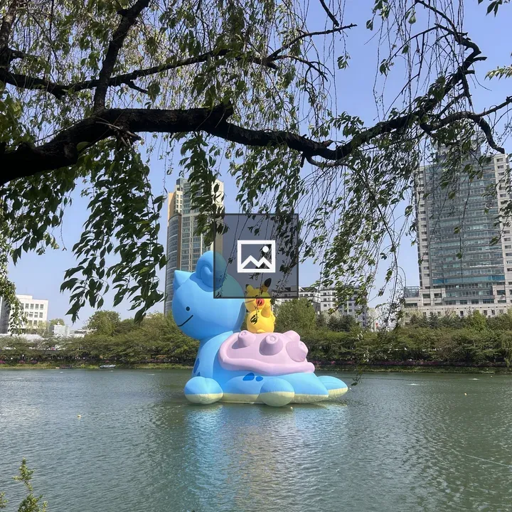 Blue inflatable cat sculpture on lake