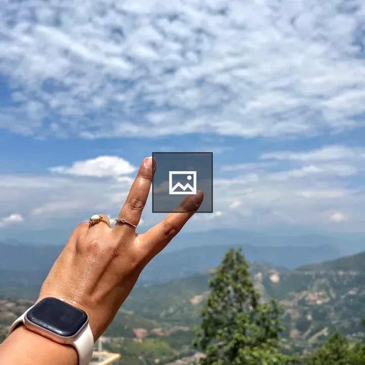 Peace sign hand against hills