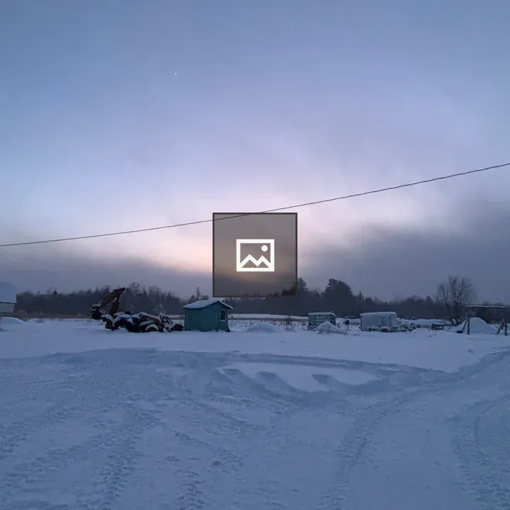 Snowy farm scene at sunset