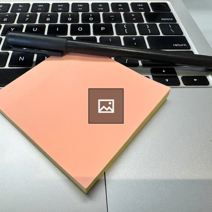 Black pen and peach notes on laptop