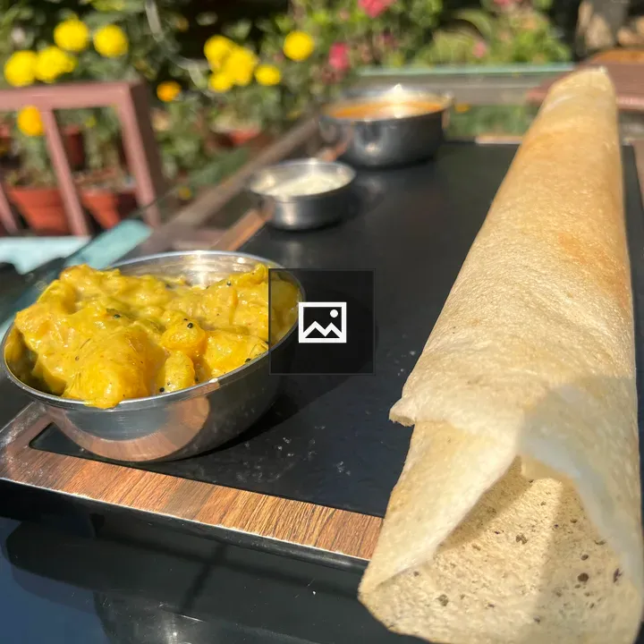 Dosa on wooden tray with curries