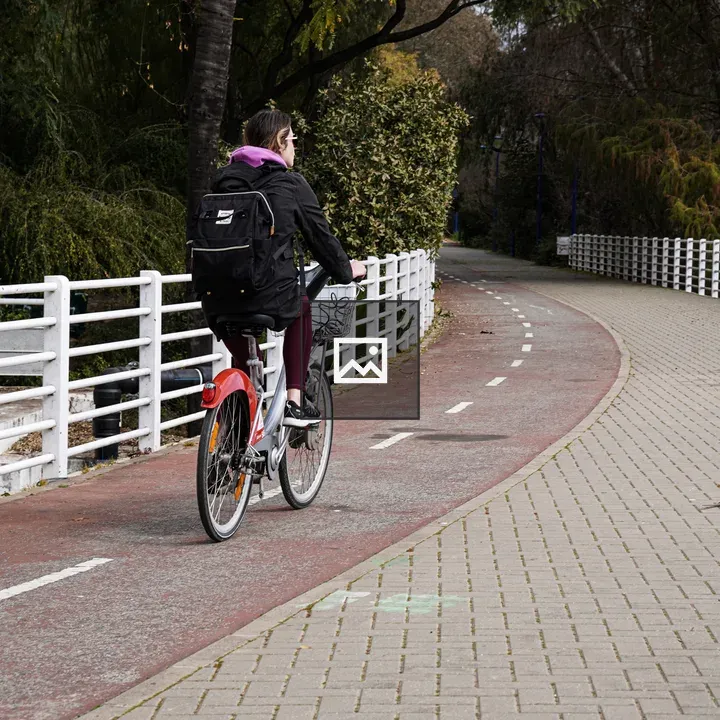 Woman on Bicycle by White Fence
