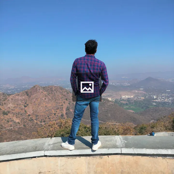 Man in Plaid Shirt Facing Mountains