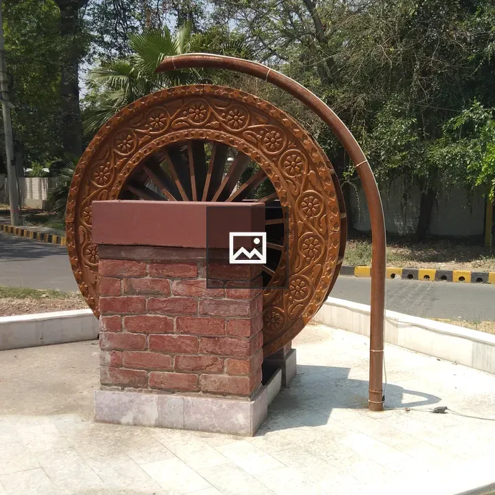 Water wheel sculpture on brick pedestal
