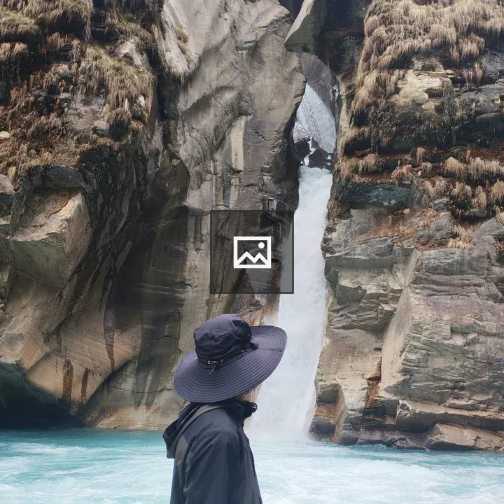 Person by Turquoise River with Rock Formations