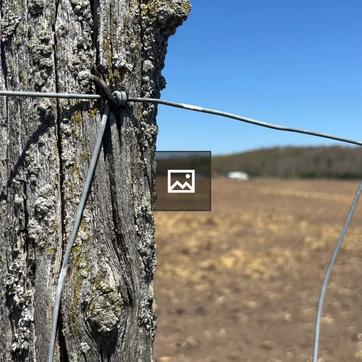 Old fence post with distant farm