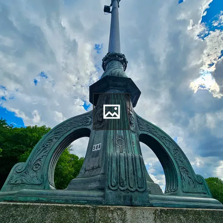 Ornate lamppost against cloudy sky