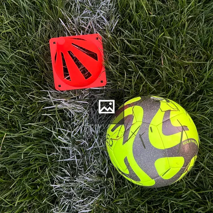 Neon soccer ball and cone on grass