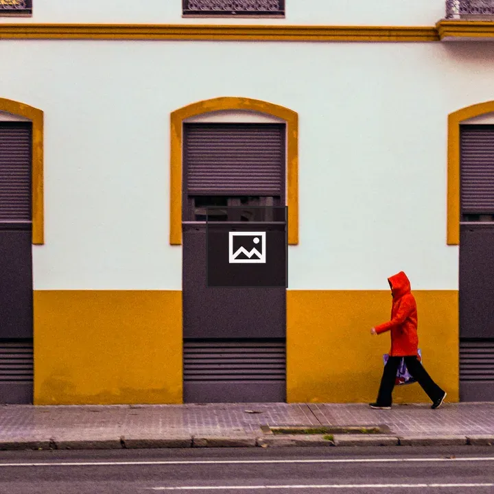 Person in red raincoat near building