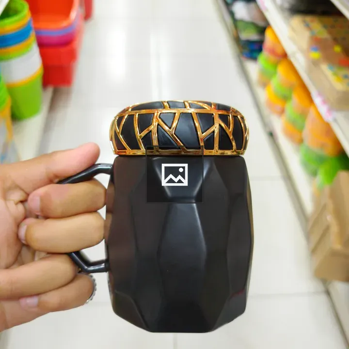 Hand holding black faceted mug