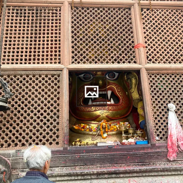 Portrait of person beside deity sculpture