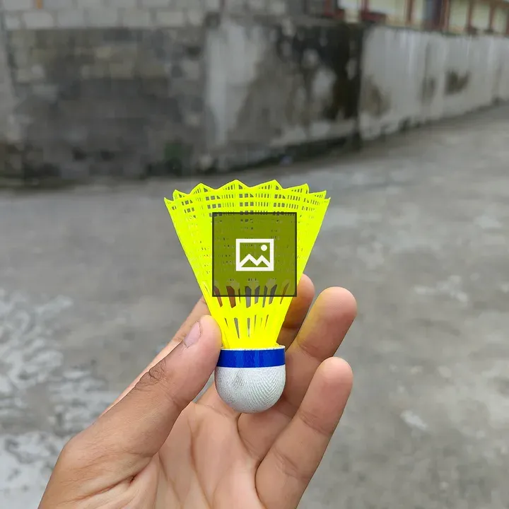 Hand holds yellow shuttlecock