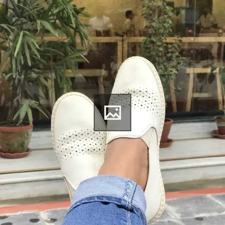 Feet in blue jeans and white loafers