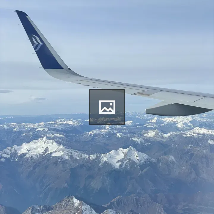 Airplane Window View Over Snowy Peaks