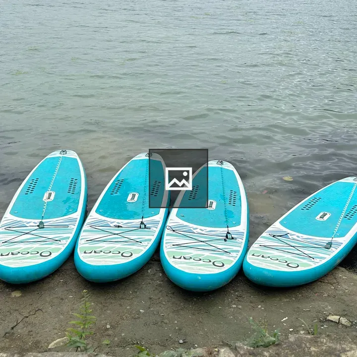 Four turquoise paddleboards on shore