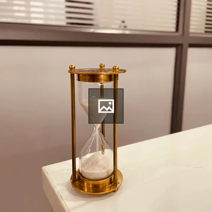 Brass hourglass on white table